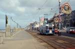 Ein Single Car der Straßenbahn Blackpool fährt die Strandpromenade entlang zum Pleasure Beach (April 1992). Die Bezeichnung  Single Car  weist darauf hin, dass die Fahrzeuge früher mit Anhänger verkehrten. Die Bahn verbindet Fleetwood im Norden und Starr Gate und führt zu einem großen Teil direkt an der Irischen See entlang. Blackpool war früher ein beliebtes Urlaubsziel der britischen Arbeiterklasse und macht heute noch entlang der Küstenpromenade den Eindruck eines riesigen Vergnügungszentrums. Dazu passen die farbenfrohen Fahrzeuge.