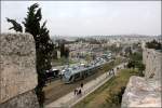 . Von der Stadtmauer aus gesehen -

Die Citadis-Tram hat die Haltestelle Damascus Cate verlassen und fährt den Hügel an der Jerusalemer Stadtmauer entlang hinauf. Im Hintergrund Gebiete von Ostjerusalem und der Mount Scopus.

18.03.2014 (M)