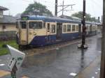 Serie 111 u.113 im Regen: Steuerwagen KUHA 111-2159 in Ôto (östlich von Tokyo). Im Vordergrund ein Lesegerät, mit dem die Fahrgeäste beim Betreten des Bahnsteigs ihre elektronische Karte einlesen und beim Verlassen des Bahnsteigs den Fahrpreis abbuchen können. 1.Juli 2010. 