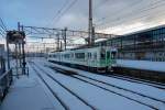 Serie 701 des Bezirks Morioka - im Schatten des Shinkansen: Neben dem imposanten Shinkansen-Bahnhof von Morioka fährt früh am Morgen Zug 701-1026 aus.