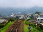 Matsu-ura-Bahn: Triebwagen 604 wartet in der Station Kita Sasebo (Sasebo Nord). Das feuchte und stickig-schwüle Klima hüllt die hohen Berge in Dunst. 26.Juli 2013.  