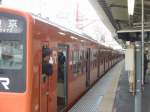 Serie 201: Die orangen Züge der S-Bahn Tokyo (JR) (Chûô-Linie). Der Schaffner kontrolliert: Alle eingestiegen, Ausfahrtsignal offen, Türen können geschlossen werden, keine gefährliche Situation am Bahnsteig. Tokyo-Musashi Sakai, 1.April 2007.