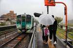 Lokalverkehr auf Shikoku - der Nordosten: Zwei Schüler sind aus Triebwagen 1509 ausgestiegen und kämpfen nun gegen Wind und Regen. Kuwano, 3.April 2015. 