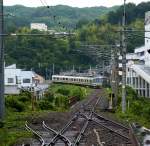 Serie 221: Ausfahrt des 6-Wagenzugs mit Endwagen KUMOHA 221-3 aus Rokujizô südlich der Stadt Kyoto. Man beachte die bei praktisch allen einspurigen Strecken vorhandenen  blinden  Ausfahrtsgleise, die bei Rot immer auf Ablenkung stehen. Doch auch bei Grün gibt der Wagenführer ein deutliches Zeichen mit dem ganzen Arm und schreit laut  Ausfahrt frei!  bevor er den Zug in Bewegung setzt. 18.Juni 2011. 