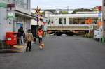 Japanische Stadtquartiere - ein JR-Zug der Serie 221 am Bahnübergang von Ôbaku an der Linie zwischen Kyoto und Nara.