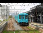 Serie 105 (viertürig) - mit dem Regionalzug durch die Dörfer im Herzen Japans: Begegnung mit Steuerwagen KUHA 104-503 (ehemaliger Zwischenmotorwagen eines Tokyo-S-Bahnzugs, dem man die Motoren ausgebaut und einen neuen Führerstand angebaut hat), Unebi, 24.März 2015. 