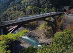 Die Haltestelle Hozukyô an der Strecke von Kyôto ins Hinterland. Ein S-Bahnzug Serie 221 durch die Schlucht über dem wilden Fluss. 8.November 2018 