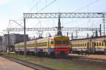 Beim Blick auf die Triebwagen an den Bahnsteigen im Hauptbahnhof Riga  berragen im Hintergrund die Trme der Altstadt die Szenerie.