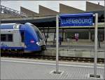 Harmonie in blau am 26.09.2010 im Bahnhof von Luxemburg. Die SNCF Computermaus passt farbllich sehr gut zum neuen Bahnhofsschild. Leider war das Schild nur ein Provisorium, am 02.12.2010 standen nur noch die leeren Pfosten am Bahnsteig. (Hans) 
