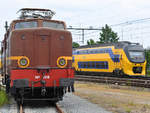 Vertreter der Vergangenheit und der Gegenwart des holländischen Schienenverkehrs. Im Vordergrund steht die Elektrolokomotive No. 1218, im Hintergrund fährt ein moderner Triebzug der Baureihe 8400 vorbei. (Blerick, Mai 2019)