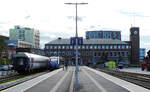 Das imposante Bahnhofgebäude von Bodö. Am Bahnsteig wartet der Regionalzug nach Mosjoen auf die Abfahrt. Links stehen Reisezugwagen mit besonderer Form im Stilllager. Bodö, 22.8.2024