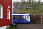 Bei Sonnenschein wäre dies ein prächtiges, farbenfrohes Bild: der blau-weisse Arctic Train neben dem roten Bahnhofgebäude vor der grünen Landschaft mit blauem Himmel. Rombak, 16.8.2024