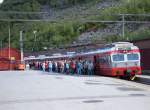 69 669 in modernen Farbdesigne nach Bergen am 14.06.2006 im Bahnhof Myrdal, Passagiere vom Kreuzfahrschiff Arielle, die mit der Flambahn nach Myrdal gekommen sind, drngen zur Weiterfahrt nach Voss in den Zug.