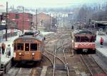 Vor einigen Tagen wurde ein Bild der auf Stromschienenbetrieb umgestellten Holmenkollenbahn veröffentlicht. Hier zum Vergleich ein Foto der Station Majorstuen aus der Zeit mit Oberleitungsbetrieb (Anfang Mai 1988). Der 1951 von Skabo gelieferte Tw 603 steht als Linie 15 vom Holmenkollen kommend zur Abfahrt in den Tunnel zur Endstation Stortinget bereit. Rechts ist der 1980 von Strommen gebaute Tw 1320 auf der Linie 14 nach Kolsas unterwegs. Während zu diesem Zeitpunkt auf dem östlichen Netz bereits Stromschienenbahnen verkehrten, gehörte die Holmenkollenbahn zu den Vestlige Baner (Westlichen Bahnen) mit Oberleitungsbetrieb. Später wurde sie in das T-bane-Netz (Tunnelbane) integriert und 2009 auf Stromschienenbetrieb umgestellt. 