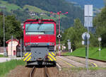 Diesellok mit ein paar Schildern und Signalen in der Nachmittagssonne.