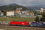 1116 180 mit Güterzug bei Bruck/Mur am 27.09.2016. Im Hintergrund ist die Südeinfahrt der Stadt mit dem Schloßberg zu sehen.