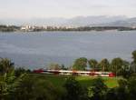 Mit Blick auf die im Hintergrund liegenden Berge des Alpsteins fhrt REX 5560 von Bludenz nach Lindau zwischen den Bahnhfen Bregenz-Hafen und Lochau-Hrbranz am 19.07.2012 das Bodenseeufer entlang.