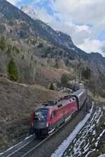 Bei Braz fährt 1116 202 mit den Wagen des RJX 160 von Bratislava nach Zürich am 19.02.2023 die Arlbergbahn Westrampe hinab