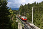 Am 28. September 2021 zeigte sich das Wetter erneut nicht von seiner besten Seite. Als die 1099.14 mit ihrem Güterzug mit Personenbeförderung den Kuhgrabenviadukt bei Erlaufklause überquerte, ließ sich die Sonne jedoch kurz blicken. Der Ötscher im Hintergrund blieb allerdings wolkenverhangen. 