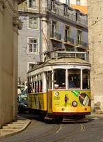 Der Strassenbahnwagen Nr. 564 mit der gelb-weisse Standartlackierung und einer Werbung unterwegs als Linie 12 nach P. Figueira am 23. April 2017 neben der  Catedral Sé Patriarcal Sé de Lisboa  in Lissabon.