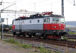 Rc6 1328 vom Regionalzug von Lulea nach Narvik setzt im Bahnhof Kiruna um, währenddem im Hintergrund ein Güterzug auf die Abfahrt wartet.