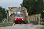 Hier befährt der Triebwagen der Inlandsbanan die Allzweckbrücke, auf der Strasse sind auf beiden Seiten die Schlagbäume gesenkt, so dass Autos und Fussgänger warten müssen. Sveg, 7.8.2024