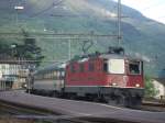 Die Re 4/4 II 11230 macht mit ihrem IR Locarno-Basel einen kurzen Halt in Faido.