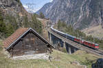 Re 4/4 II 11199 und 11191 ziehen den VSOE durch die Urner Berglandschaft und überqueren gerade die mittlere Meienreussbrücke. Aufgenommen am Nachmittag des 27.03.2022.