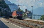 Beim Château de Chillon tritt die SBB Re 4/4 II 11266 (Re 420 266-9) mit ihrem Güterzug aus dem Schatten heraus.