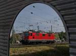 Durchblick II - Nachdem Re 4/4 11111 die Wagen eines IC von Zürich nach Singen gezogen hatte und diese Wagen von einer DB-Lok übernommen und Richtung Stuttgart weitergezogen wurden, befindet sich die Re 4/4 auf Rangierfahrt zu einem Bereitstellungsgleis. Der Blick durch den Eingang zu einem Parkhaus wurde am 31.05.2015 in Singen aufgenommen.