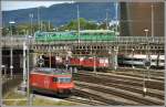 Re 460 013-8 und einige Re 420 warten auf neue Aufgaben und auf der Münchensteinerstrasse überquert ein Be 4/4 + B4 die Geleise beim Bahnhof Basel SBB.