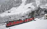 Die Re 4/4 II 11158 ist mit einer weiteren Re 4/4 II der ersten Bauserie und einem Interregio bei Schneegestöber Richtung Norden unterwegs. Wassen, 26.11.2015 