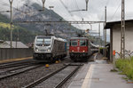 187 006 der BLS und die Re 4/4 - 11157 fahren gleichzeitig in den Bahnhof Erstfeld ein, aufgenommen am 23. Mai 2016.