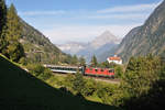 Die Re 4/4 II 11243, welche von SBB Cargo an den Personenverkehr vermietet ist, fährt hier bei Wassen mit einem Interregio auf der mittleren Ebene talwärts. Im Hintergrund die Wassener Kirche, sowie direkt darüber die markante Chli Windgällen. Aufgenommen am 06.10.2016