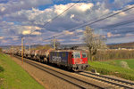 Am abend fährt die Re 4/4 II 421 390-6 bei einer von Saharastaub geprägten Wolkenstimmung in Umiken mit einem Mineralölzug vorbei.Bild vom 9.4.2016