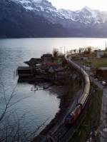 Die ber die Berge des Alpsteins kommende Morgensonne bei Tiefenwinkel am Walensee lsst die Wagendcher des von einer Re 460 gezogenen IC 562 von Chur nach Basel SBB am 02.04.2010 glnzen.