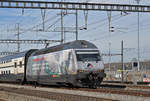 Re 460 107-6, mit der Alp Transit Werbung, durchfährt den Bahnhof Muttenz.