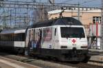 Re 460 041-7 mit der redcross.ch Werbung durchfährt den Bahnhof Muttenz.