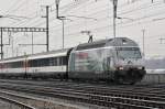 Re 460 107-6 mit der Gotthardtunnel Werbung durchfährt bei leichtem Schneefall den Bahnhof Muttenz.