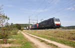 Bei hochsommerlichen Bedingungen ist ein umgeleiteter UKV-Güterzug mit führender ES 64 F4 - 112 auf der Einspurstrecke bei Rafz unterwegs.