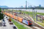 482 047 durchfhrt mit einem Containerzug vor der imposanten Kulisse der Praterbrcke, des Donauturmes und der Uno City den Wiener Donaukaibahnhof.