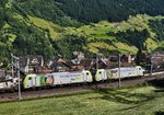 BLS Re 486 508-5 und BLS Re 486 506-9, fahren oberhalb der Ortschaft Wassen, mit einem Containerzug talwärts.