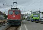 Eine Ae 6/6 bringt Abwechslung ins von BLS Ninas geprgte Betriebsgeschehen im Bahnhof Murten:   Whrend der Regionalzug 4921 von Payerne kommend einfhrt, wartet die Ae 6/6 auf die Ausfahrt Richtung