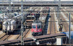 Hochbetrieb im Rangierbahnhof Limmattal am 8. April 2015. In der Einfahrgruppe ist gerade die Re 6/6 11626  Zollikofen  mit einem Güterzug angekommen. Sobald der im Vordergrund über den Ablaufberg rollende Zug zerlegt ist, wird sie in die Lokwartegruppe am anderen Ende der Richtungsgruppe gestellt. Auf den Nebengleisen warten weitere Züge, deren Loks bereits weggestellt wurden, auf die Zerlegung.