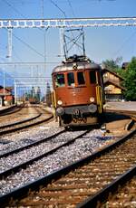 Schweizer Ellok Ae 6/8 208 (Bern-Lötschberg-Simplon-Bahn) entfernt sich mit einem langen Zug vom früheren Bahnhof Leissigen (1988)