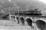 BLS:  Kurzer Personenzug Brig-Domodossola mit der Ae 6/8 203 auf voller Fahrt in Domodossola im Jahre 1979.