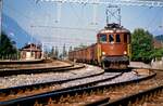 Schweizer Ellok Ae 6/8 208 der Bern-Lötschberg-Simplon-Bahn entfernt sich mit einem langen Zug vom früheren Bahnhof Leissigen (1988)