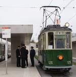 AGMT BC Association Genevoise du Musée des Tramways Museumsbahn Blonay-Chamby: Be 2/2 125 (SIG/Sécheron 1920 und Ersatz der Elektroausrüstung MFO 1946/47), Linie 1 Rive-Carouge-Bachet und zurück, Haltestelle Lancy-Bachet, Genf, 3. Novmber 2024 ( Festival Trams ). Die kurze Wartezeit vor der Rückfahrt reicht den AGMT-Bénévoles (in alten Trämler-Uniformen) für einen kleinen Schwatz.  