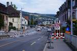 ASm BTI Aare Seeland mobil AG Biel-Täuffelen-Ins-Bahn: Neubau Niveauübergang Hauptstrasse und Station, Nidau, 15. August 2023. Bereits liegen die Gleise. Die Bahn quert die Hauptstrasse in einem Kreisel (im Bildhintergrund vor der Station mit einem in den Kreisel einfahrenden Bus der Verkehrsbetriebe Biel). Die drei Liegenschaften im Bild links der Gleise werden neu über einen Weg entlang der Gleise, ausgehend vom Kreisel und ohne Gleisquerung erschlossen.   