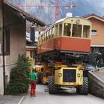 BLM Bergbahn Lauterbrunnen-Mürren: CFe 2/4 (SIG/MFO 1913), Transport Winteregg-Lauterbrunnen mit dem Spezialfahrzeug  Castor und Pollux , Isenfluhstrasse, Lauterbrunnen, 24. Oktober 2024. Der Wagenkasten ist in dieser Kurve zentimetergenau an vorstehenden Hausdächern vorbei zu manöverieren.